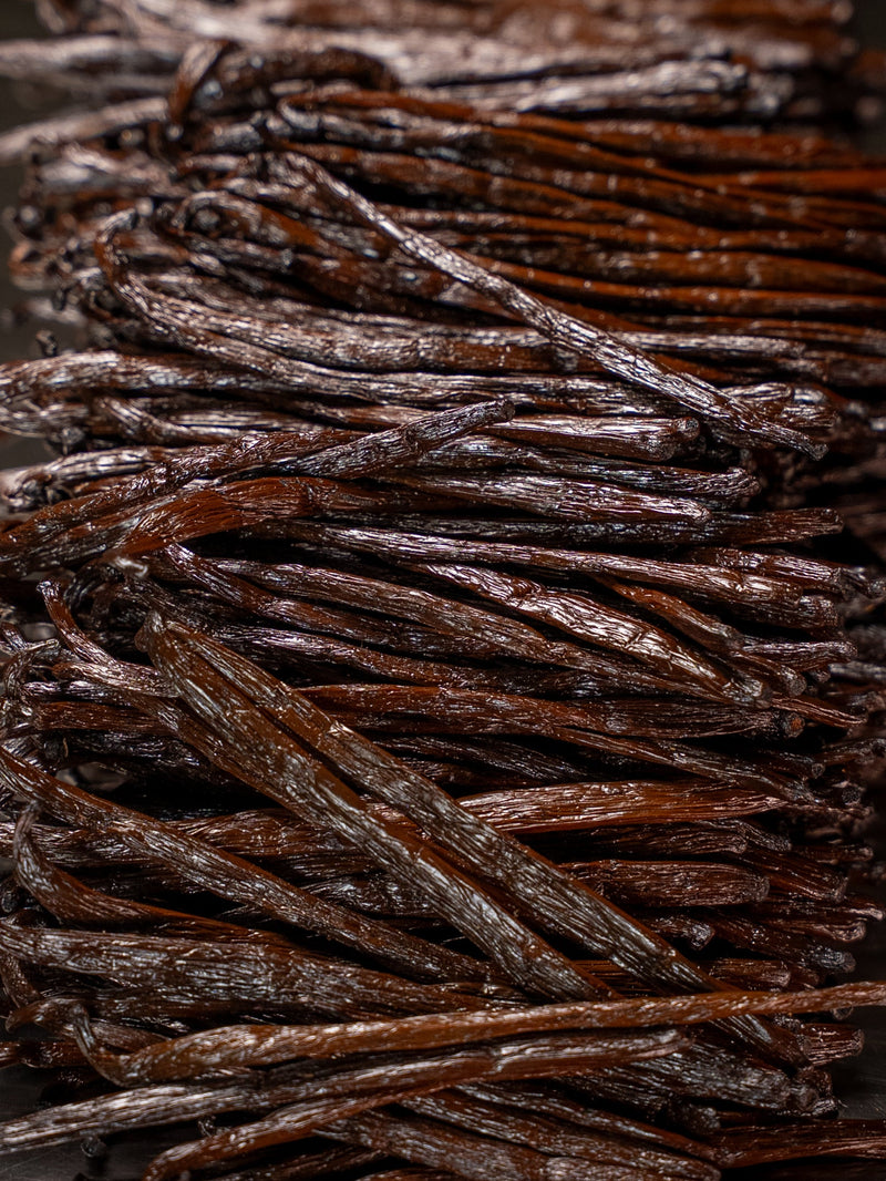 Close-up of premium Madagascar Bourbon vanilla beans, showing their glossy dark brown color and natural texture.