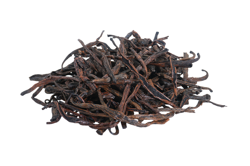 Pile of loose Madagascar Bourbon vanilla beans and cut pieces, showing their natural dark brown color and dried texture.